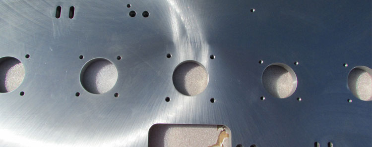 Image of metal that has gone through our cnc machining services process. This image shows a large metal piece with various holes machined into it. This was custom made for a client.